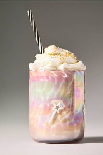 Whipped cream-topped iridescent mug with straw, featuring a magical wand design, evokes whimsical benignant   for unsocial   buying  experiences