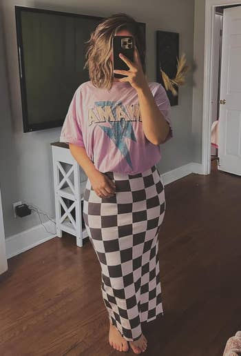 reviewer wearing a pink tee over the black and white checkered dress