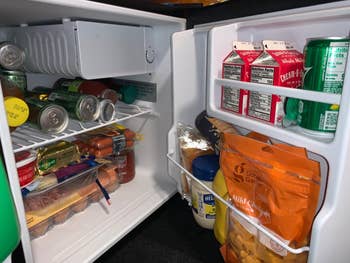 a reviewer photo of the inside of the mini fridge packed with food drinks and snacks