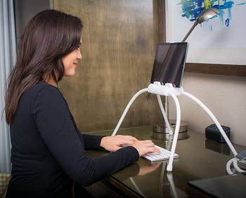 model sitting at a desk with the tablet propped up on the desk with the stand