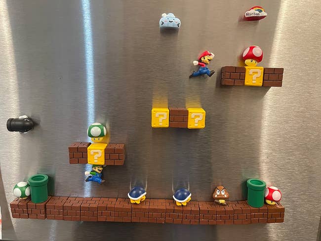 Super Mario themed fridge magnets arranged to mimic a level from the game, featuring Mario, coins, and question blocks