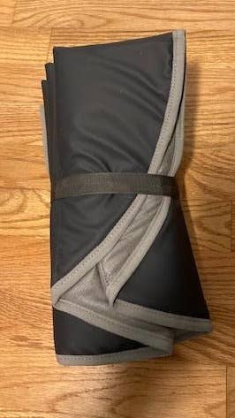 Pair of folded black workout leggings with a gray waistband on a wooden floor