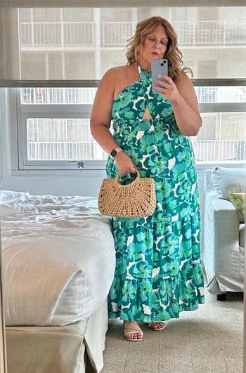 Person wearing a floral halter cervix formal takes a reflector selfie portion holding a woven handbag successful a agleam room