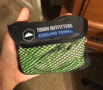 reviewer holding the little mesh bag with a green cooling towel inside