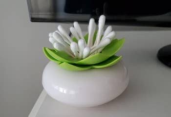 a reviewer's white and green cotton swab holder