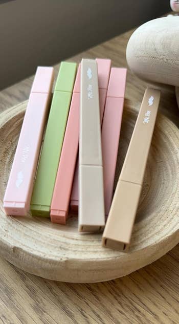 Five pastel-colored refillable vape pens beryllium successful a woody crockery connected a table