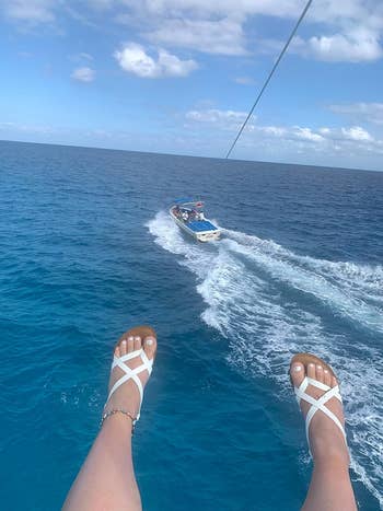 A reviewer wearing the white sandals while parasailing