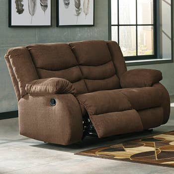 the dark brown loveseat with one side slightly reclined with the footrest up