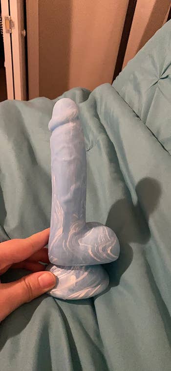 Reviewer holding blue marbled dildo