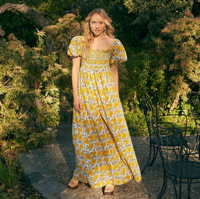 a model in a yellow floral maxi dress with puffy sleeves