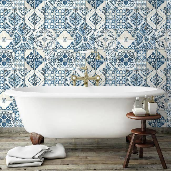 the blue tile peel and stick wallpaper on a wall behind a white bathtub 