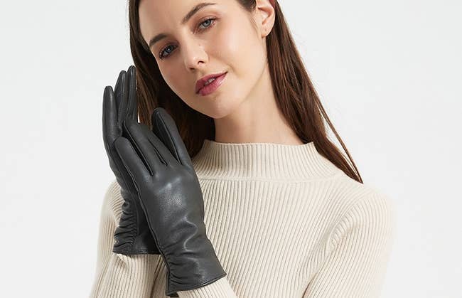 a model wearing the black leather touchscreen gloves
