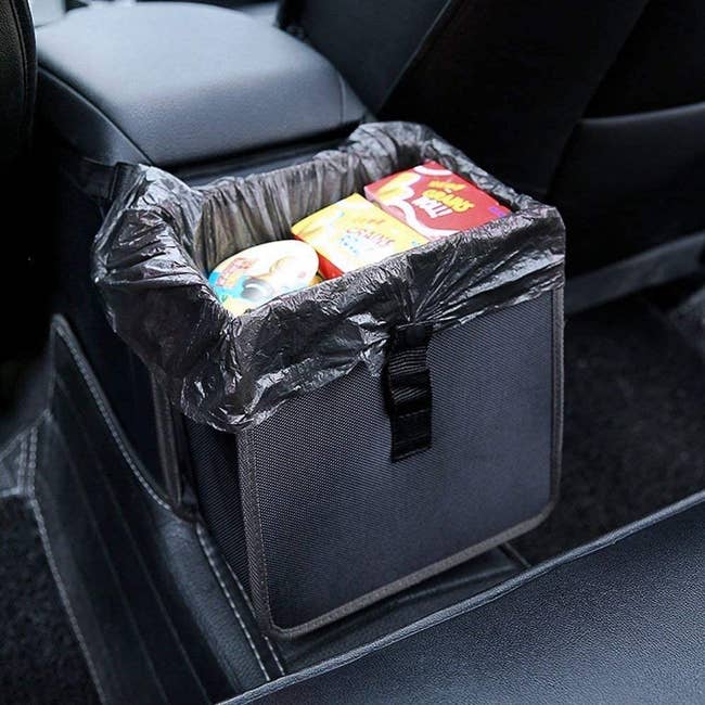 lunch box-sized black car trash can with liner bag in the backseat