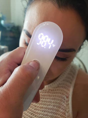 reviewer having their temperature taken, with the thermometer reading 98.4 degrees