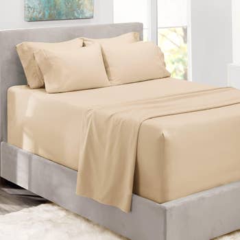Bed with a beige sheet set in a well-lit room, suitable for a shopping article about bedding
