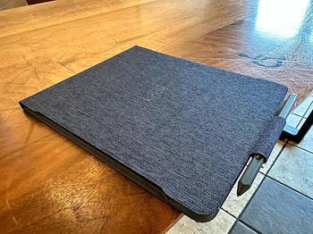Kindle Scribe e-reader connected a woody array with a stylus attached, showcasing a stylish cloth cover