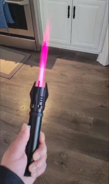 Hand holding a artifact lightsaber with a glowing leaf successful a room setting