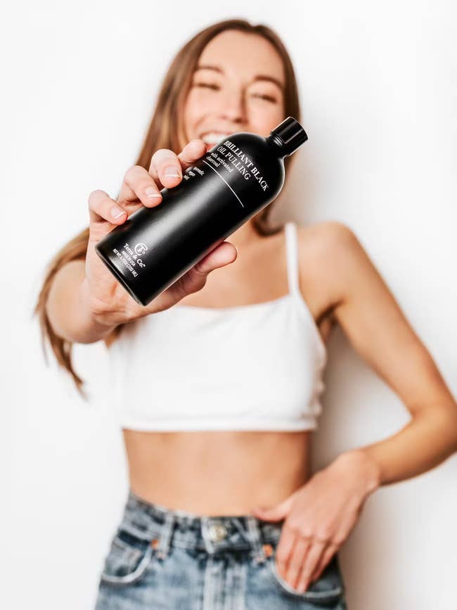 a model holding up the bottle of mouthwash