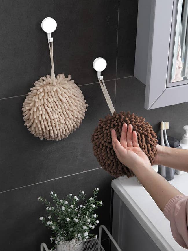 Person drying hands using a wall-mounted, fluffy, beige hand towel