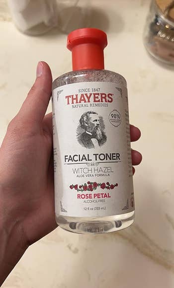 Hand holding a bottle of Thayers Facial Toner with Aloe Vera and Rose Petal