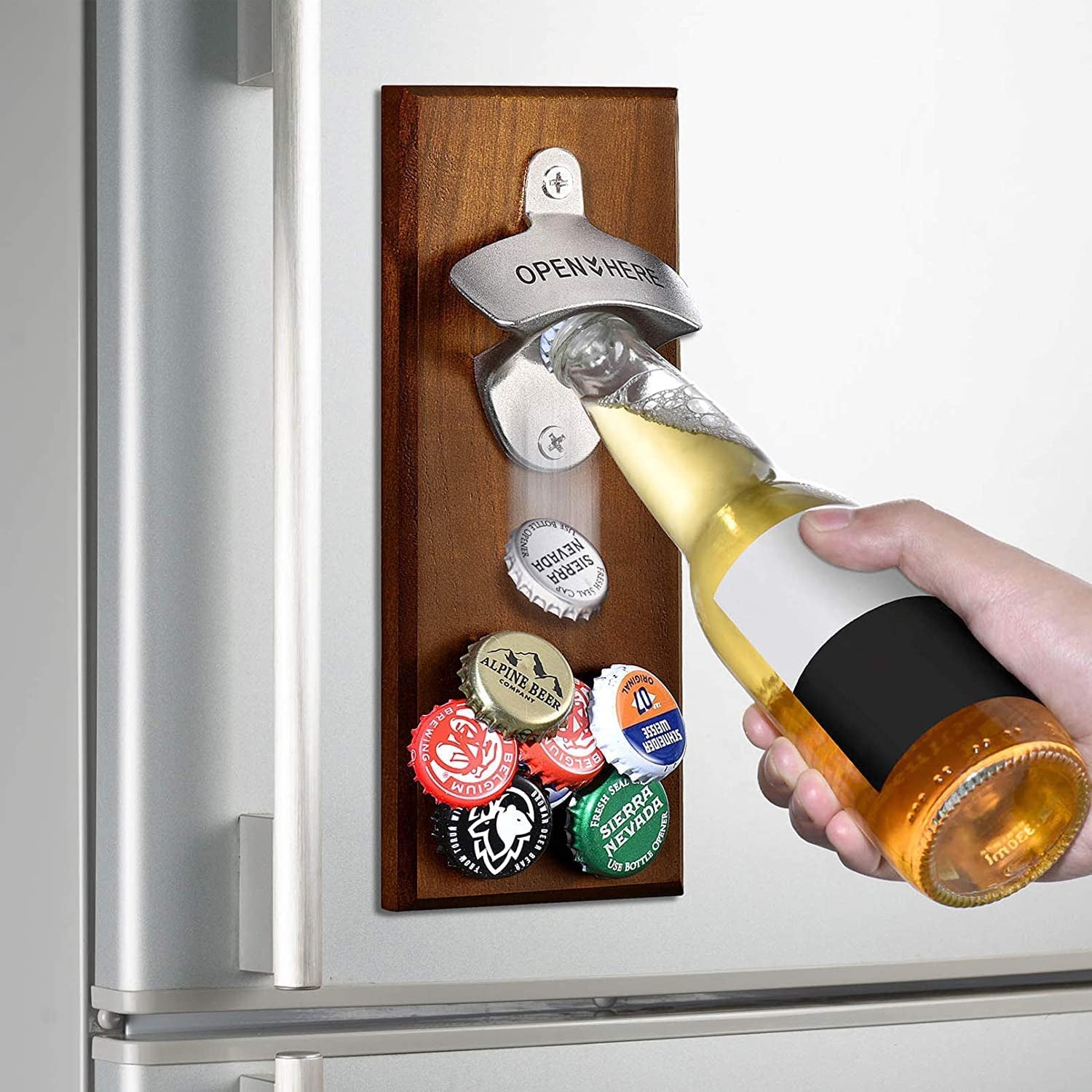 Hand hold beer bottle using opener as caps magnetically adhere to opener