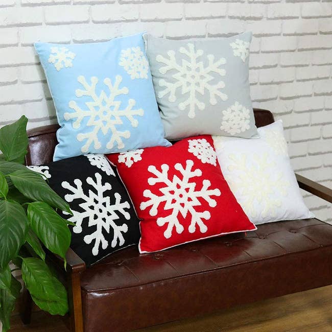 five pillow cases in different colors embroidered with white fuzzy snowflakes