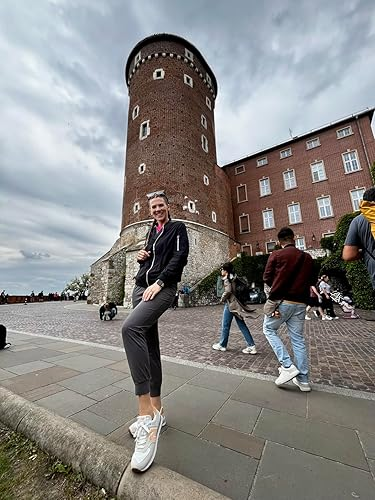 Person posing casually successful  beforehand   of a historical  ceramic  operation    and buildings, wearing casual attire and sneakers. Other visitors are nearby