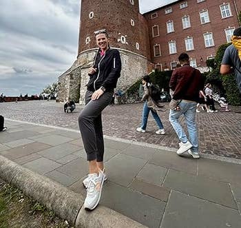 Person posing casually successful beforehand of a historical ceramic operation and buildings, wearing casual attire and sneakers. Other visitors are nearby