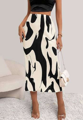 Person modeling a knee-length skirt with an abstract black and white design, paired with a black crop top and heels