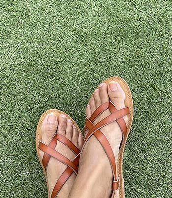 reviewer wearing the tan sandals on grass