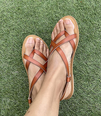 reviewer wearing the tan sandals on grass