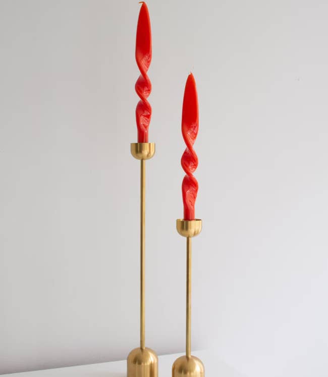 Two coral twisted candles in gold holders 