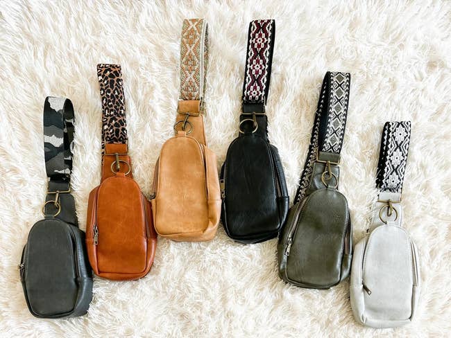An assortment of eight crossbody bags with various patterns displayed on a textured surface