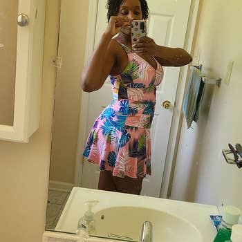 reviewer wearing the swimdress in pink with blue and green fern designs on it