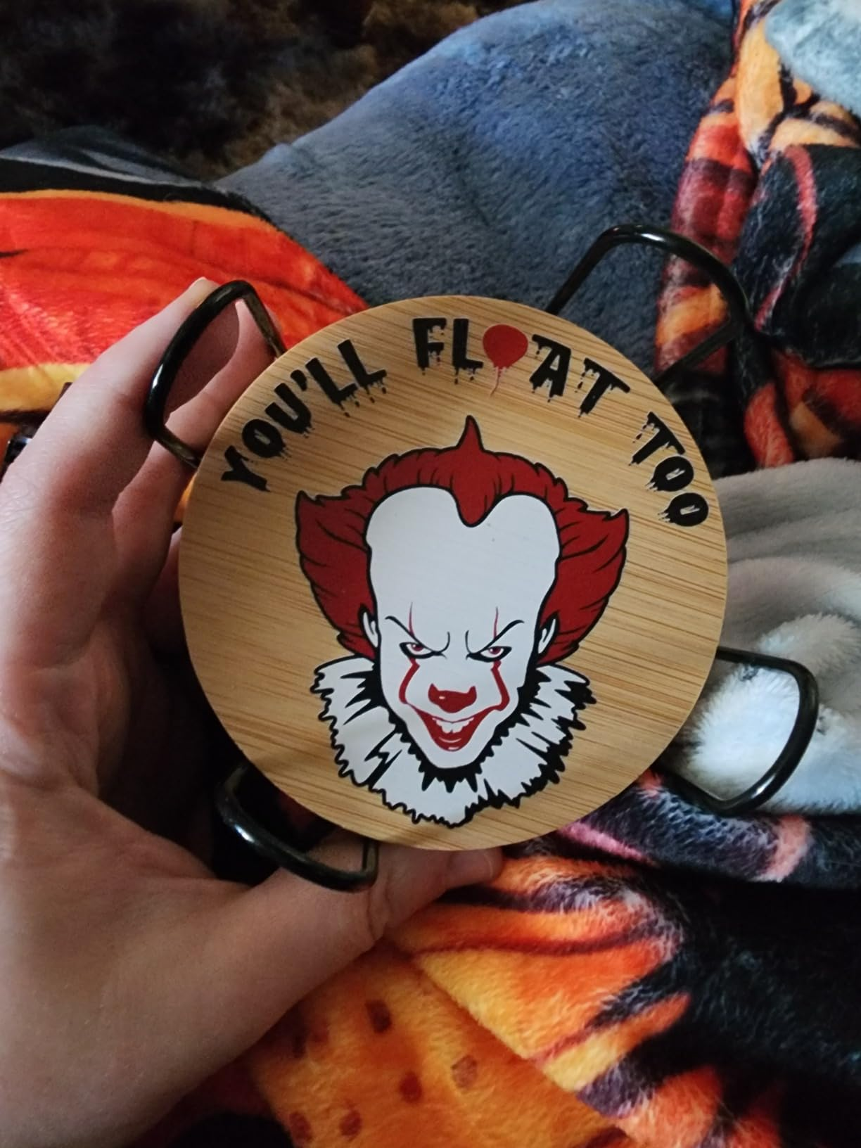 Reviewer holding a circular  coaster featuring Pennywise and the substance   