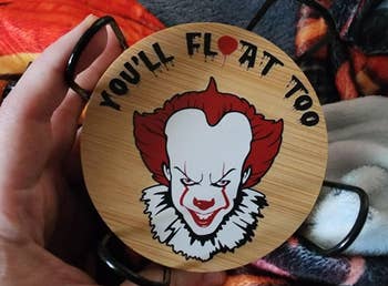 Reviewer holding a circular coaster featuring Pennywise and the substance