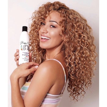model with curly hair holding the bottle of curl defining cream