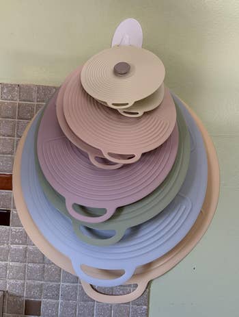 Stacked silicone cookware lids successful assorted sizes bent connected a wall-mounted holder, showcasing space-saving room organization