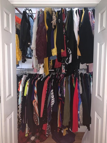the same closet with the lights turned on to clearly show all the clothes inside it