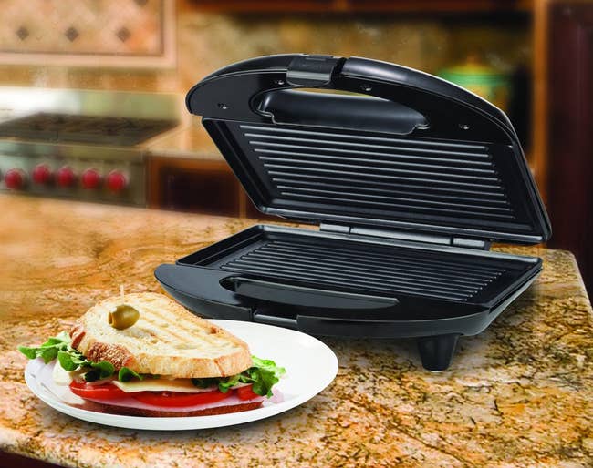 Image of the black panini press next to a sandwich