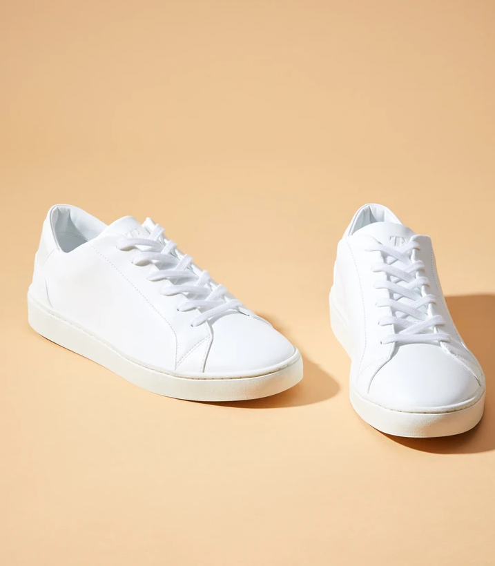 the white lace-up sneakers on an orange background