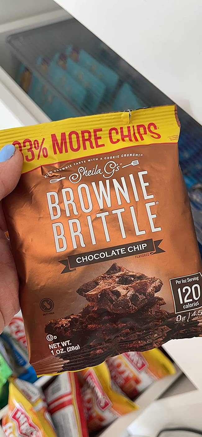 A reviewer holding a bag of the chocolate flavored brownie brittle 