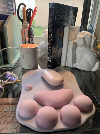 Reviewer's desk with beauty sponges, a mouse pad, books, a candle, and a dog-shaped lamp