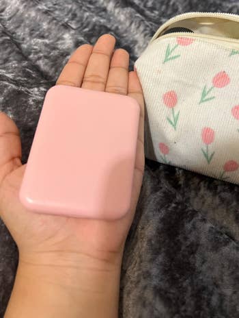 Reviewer holding a pink rectangular compact mirror