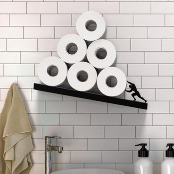 close up of shelf with silhouette of person holding up the toilet paper