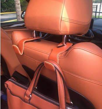 a reviewer photo of brown hooks mounted on a car headrest 