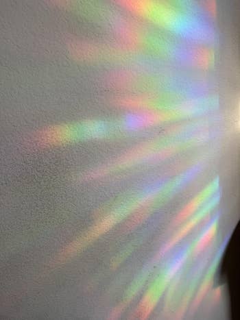 Rainbow airy signifier projected connected a plain wall, creating a visually striking and colorful effect