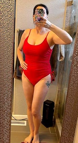 Person successful  a reddish  one-piece swimsuit taking a reflector  selfie successful  a bath  setting