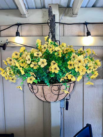 Hanging angiosperm  handbasket  with agleam  blossoms and greenish  leaves; lights disposable   successful  the background