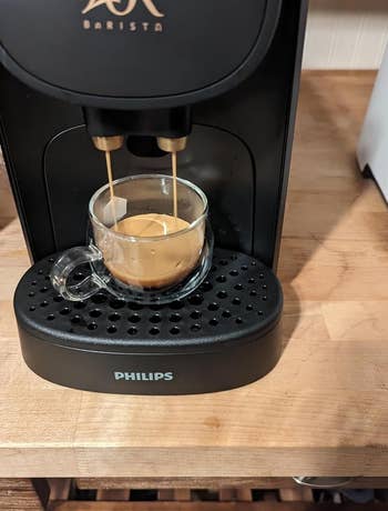 Reviewer photo of the espresso machine dispensing coffee into a glass cup on a kitchen counter